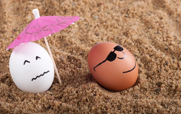 Easter funny eggs under umbrella on a sand