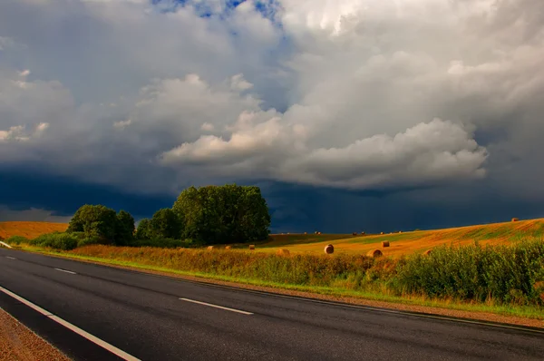 Road and field and dark cloud before rain — Stock Photo #30153599