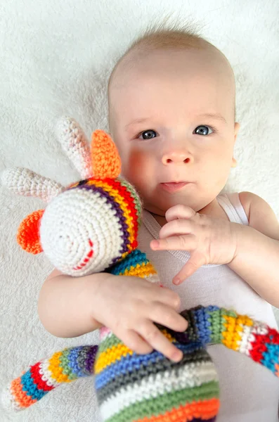 Adorable baby playing with colorful hand made crochet toy on white background