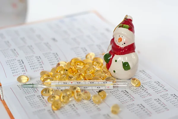 Colored pills, snowman and the thermometer on the background Datebook