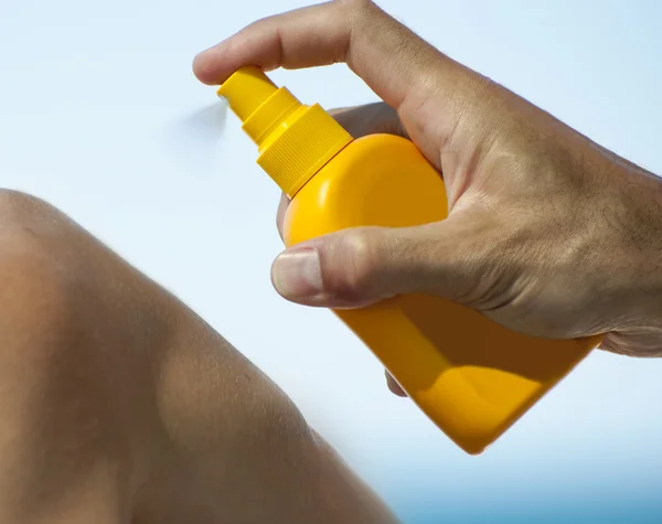 Man holding orange sun tan lotion bottle