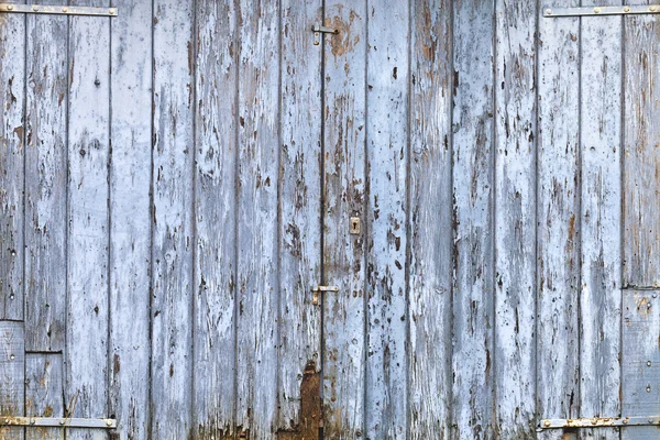 Old, grunge wood panels of wide light blue door