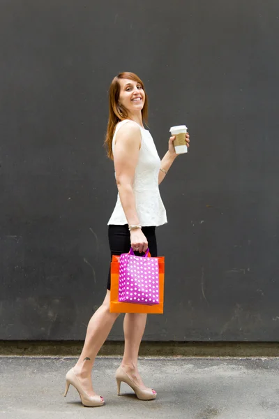 Woman with shopping bags and coffee in the city