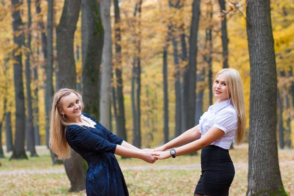 Two young girls holding hands in autumn park