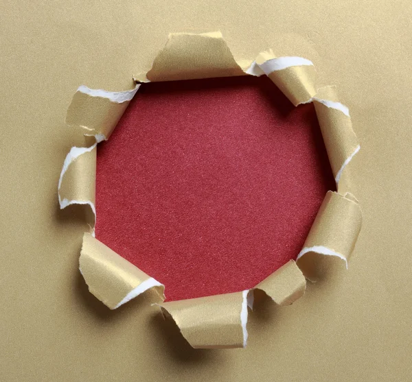 Hole ripped in gold paper — Stock Photo #26484935