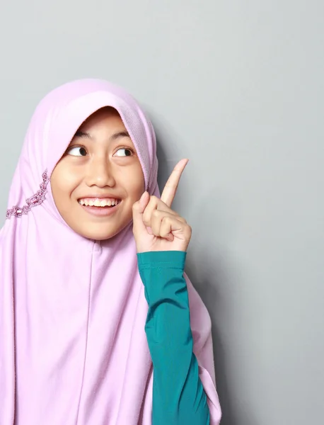 Muslim young girl pointing up