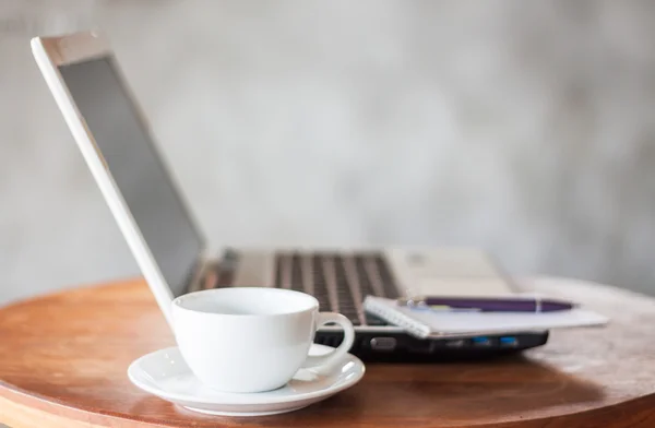 Laptop, notepad and coffee cup on wooden table