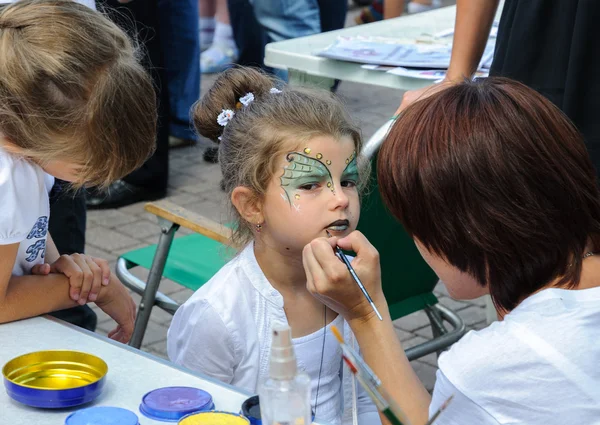 An unidentified child, painting at a girl's face on City Day of Kaliningrad