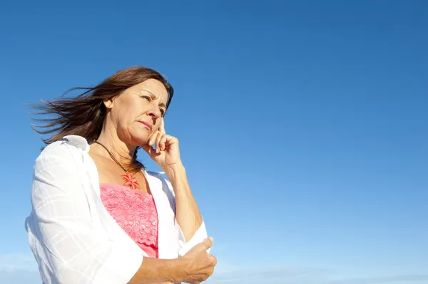 Lonely depressed senior woman sky background