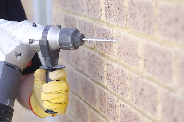 Hand holding drill at wall