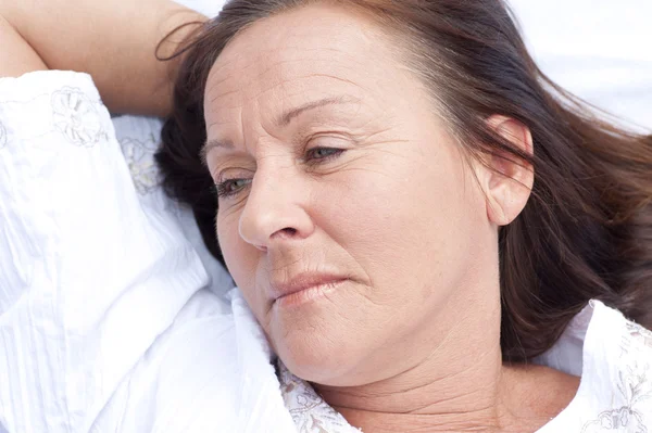 Sad contemplating mature woman resting in bed — Stock Photo #22670247