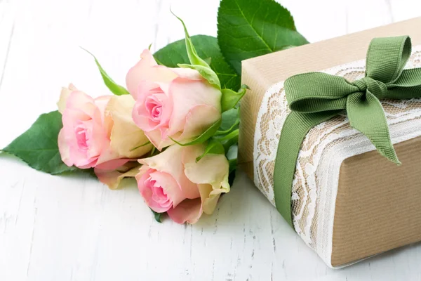 Gift box wrapped in brown paper, white lace and a green bow