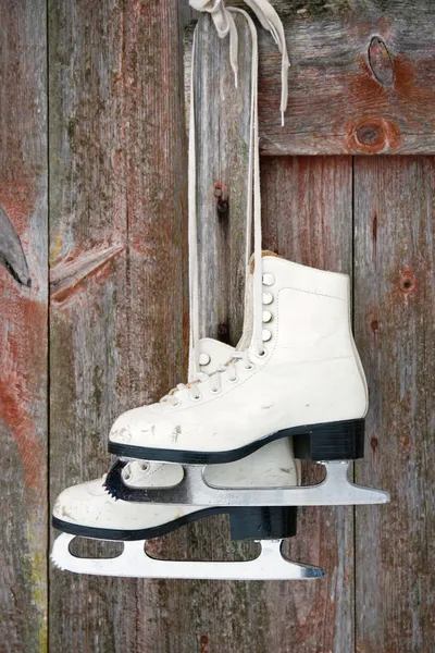 Old figure ice skates on a rustic wooden wall