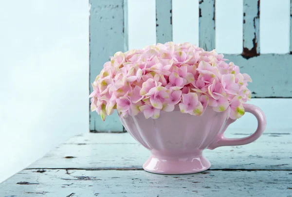 Cup full of pink hydrangea on vintage chair
