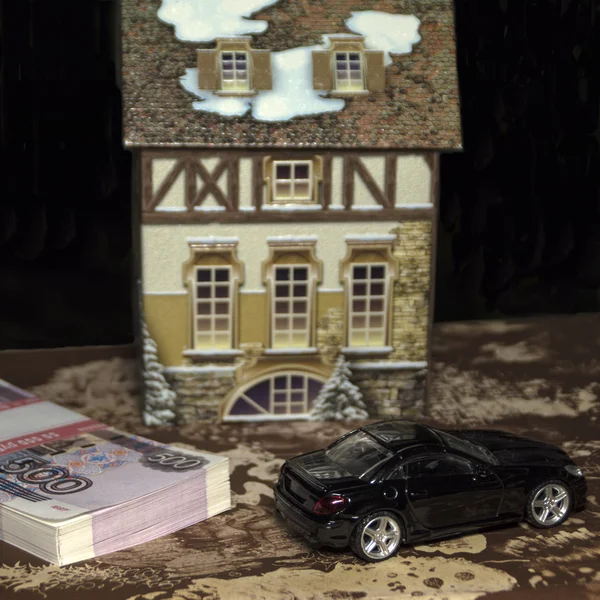 The toy car and cottage and a pile of money