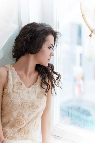 Beautiful young brunette woman looking out the window