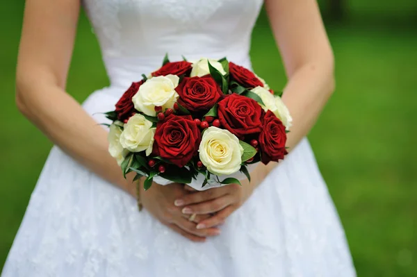Bride holding wedding flower bouquet of red and white roses