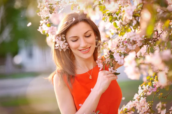 Young woman in red dress standing among blossom trees