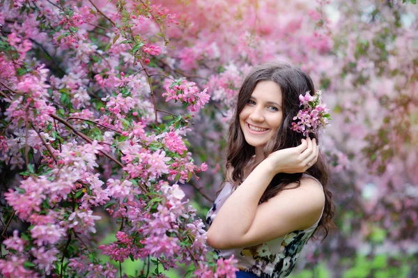 Beautiful girl in spring park with flowers lifestyle portrait, happy woman with blooming cherry tree. Skin care and beauty. Smiling teen girl in spring garden enjoying nature. Spring concept. Series.