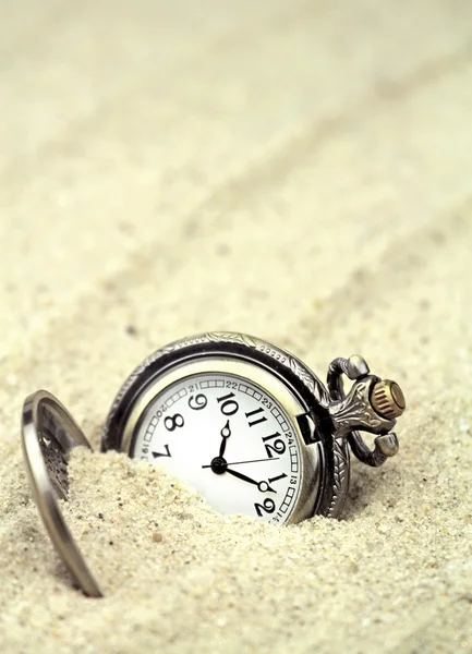 Antique pocket watch buried in sand