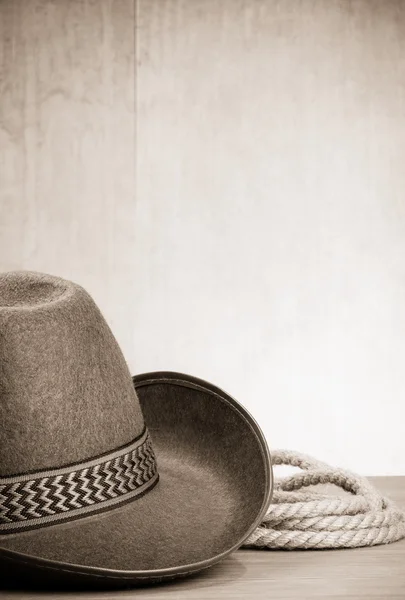 Vintage brown cowboy hat and rope at wood