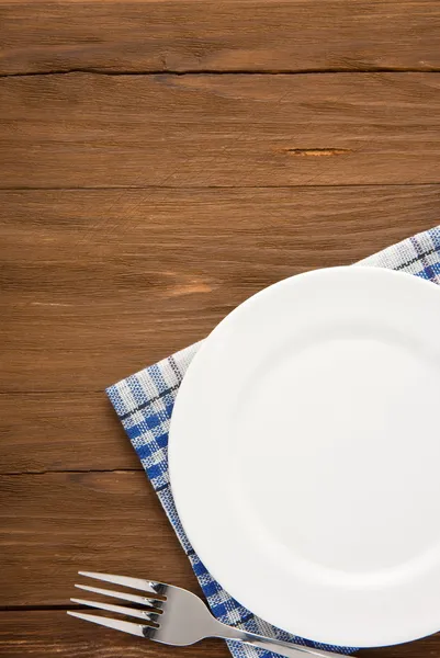 White plate and fork on wood