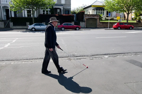 Blind man walks with a cane in the street