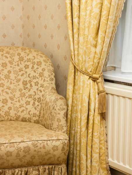 Brown vintage armchair near retro curtain