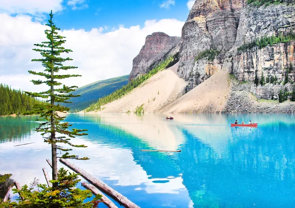 Beautiful landscape with Rocky Mountains and tourists canoeing on azure mountain lake, Alberta, Canada