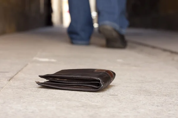 Lost wallet on the street and legs of the walking man concept