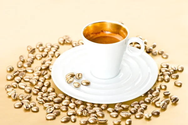 White cup of black coffee with golden beans