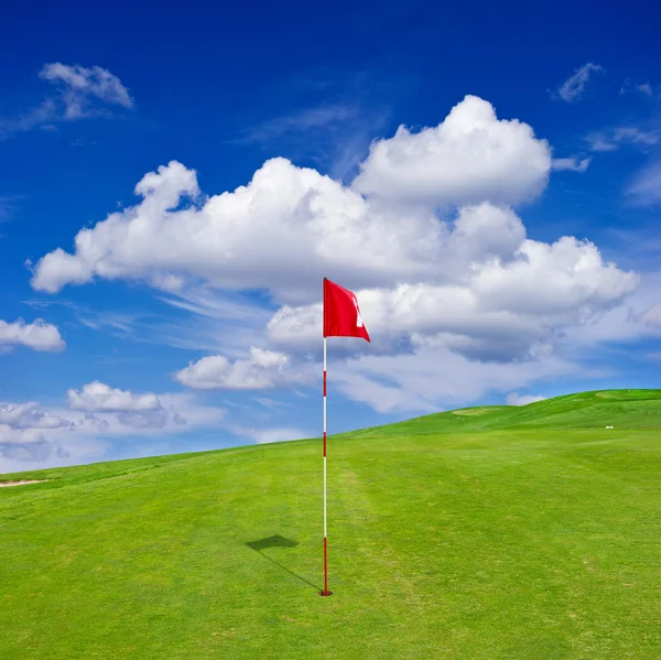 Green golf field with cloudy sky