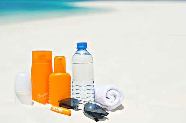 Water and sun protection cream on beach background