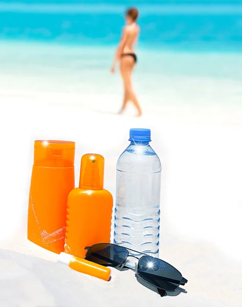 Bottle of water, sun protection cream and sunglasses on beach ba