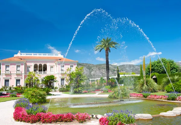Landscape with fountain, colorful flowers and blue sky