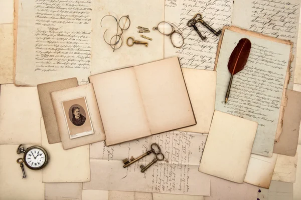 Open book, old letters, post cards, glasses, keys, clock