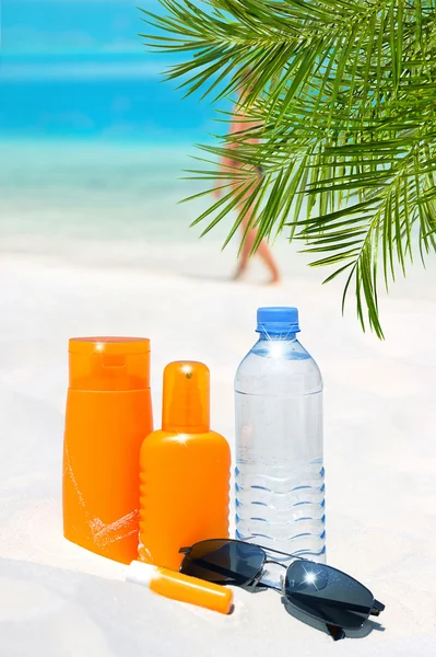 Sunglasses, water and sun protection cream on the beach