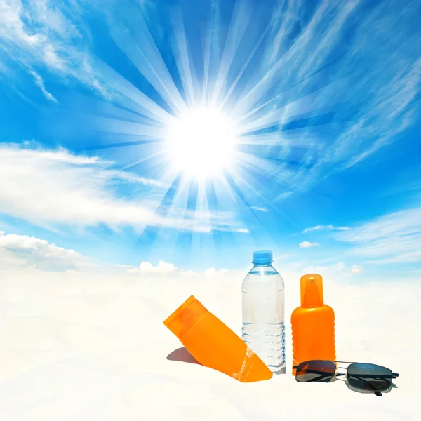 Sunscreen cream and bottle of water over sunny blue sky
