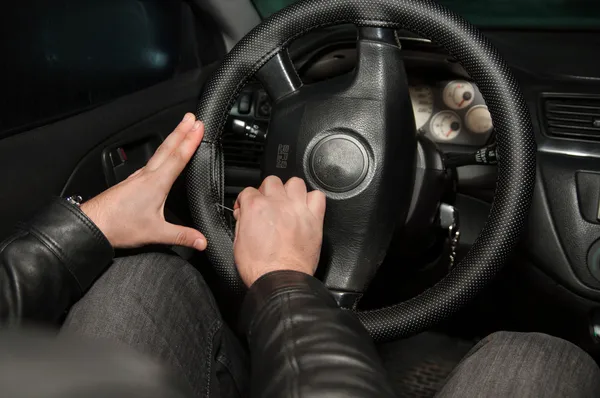 Hands sewing leather steering wheel