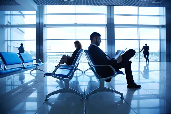 Business partners reading at the airport