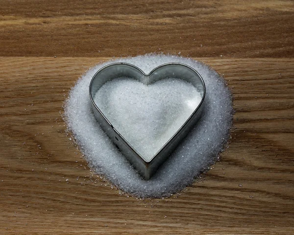 Heart shape cookie mold on a wood and sugar