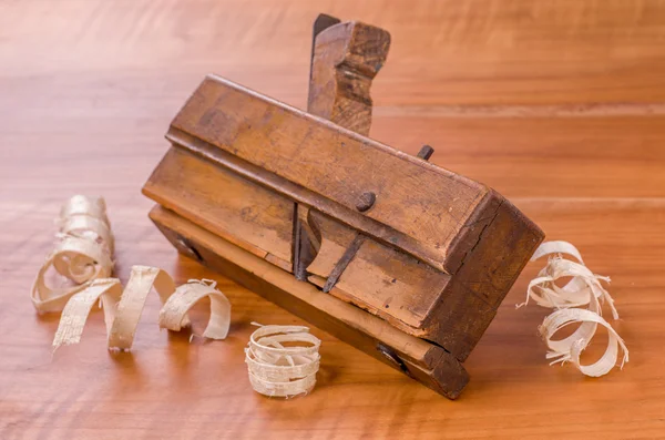 Old molding plane with shavings on a cherry wood board