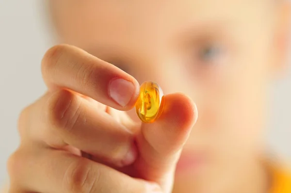 Close up of kid holding yellow pill