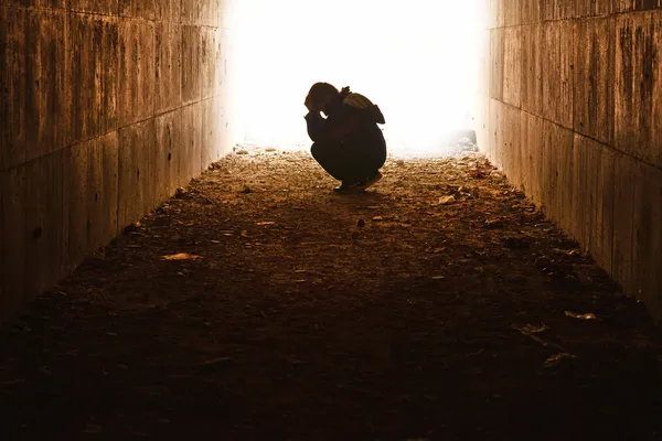 Waif sitting in the tunnel in sorrow