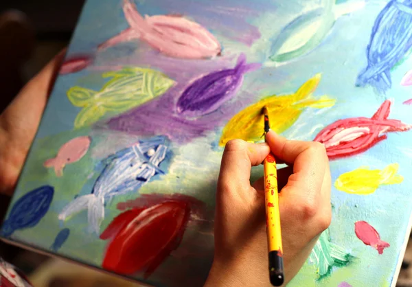 Artists hand with paintbrush painting the picture
