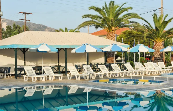 Swimming pool with sunbeds in Greece.Empty white sunbeds at the modern resort.swimming pool in a hotel.Swimming pool in small hotel yard with chaise-longues.