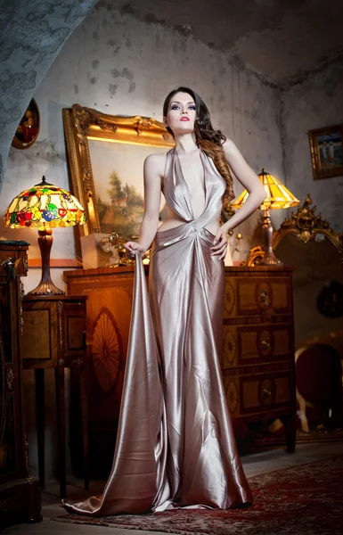 Young beautiful luxurious woman in long elegant dress. Beautiful young woman in a luxurious classic interior. Seductive brunette woman in luxury manor, vintage style