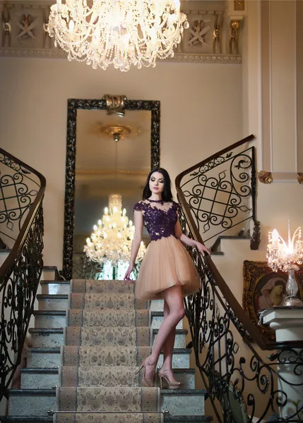 The beautiful girl in a short black and nude dress posing in a vintage scene. Young beautiful woman wearing a lace dress in an old hotel. Sensual elegant young woman in black short dress indoor shot.