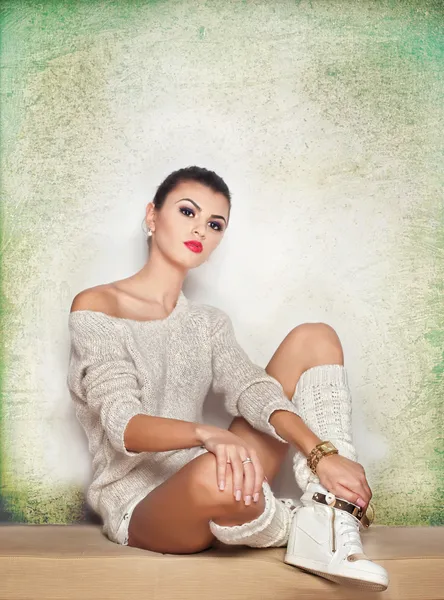 Attractive brunette model with white blouse, long stockings and high heels standing on white background. Fashion portrait of cute girl - studio shot. Beautiful fair hair woman in white posing pretty.