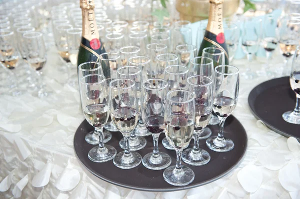 Wedding decor, wine glasses and champagne flutes on table. Decoration with bottles and glasses of champagne on festive table. Luxurious wedding decoration on restaurant table. Elegant event